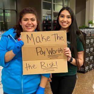 Two workers holding a sign that reads "Make the pay worth the risk!"